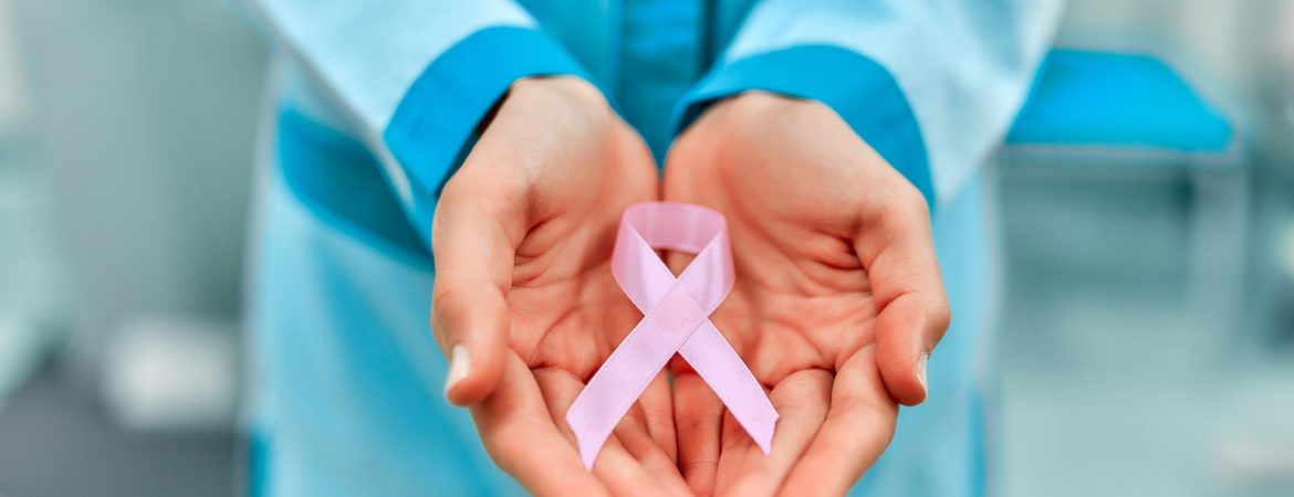 International symbol for October Breast Cancer Awareness Month. Close up of female doctor's hand holding pink awareness ribbon. Health care and medical women concept.